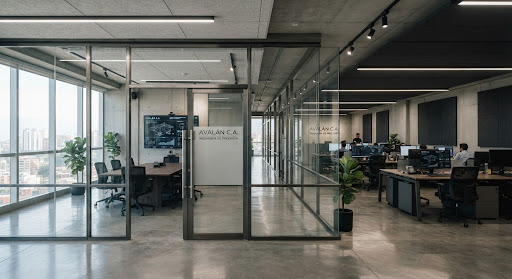 Interior de oficina corporativa con divisiones modulares de vidrio y perfiles de acero cepillado.
